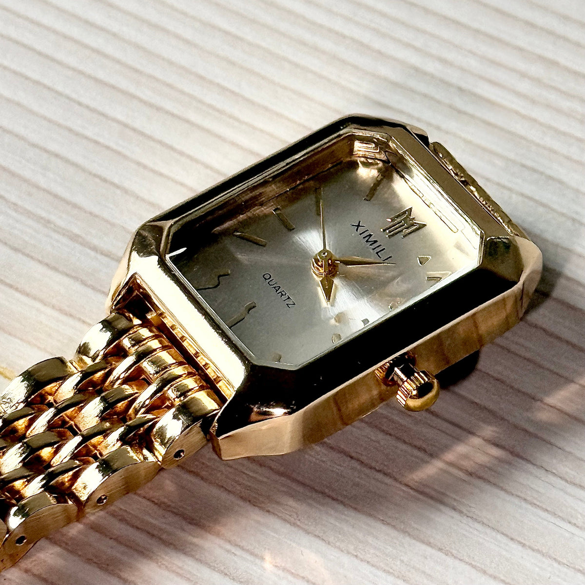Gold rectangular quartz watch close-up on wooden surface